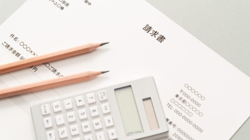 請求書と電卓、鉛筆が並ぶ机の上の写真。相続手続きで発生した高額請求をイメージ。