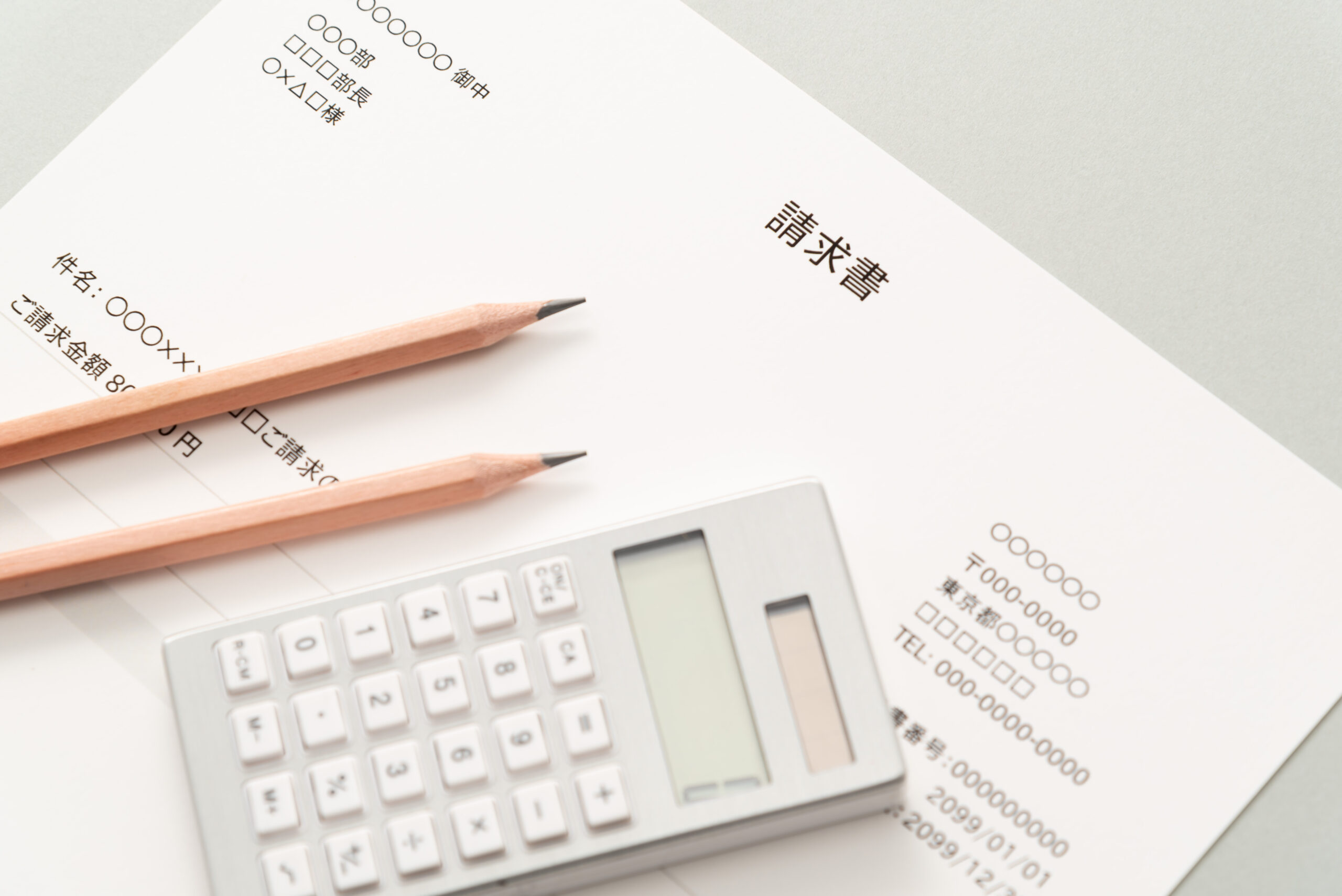 請求書と電卓、鉛筆が並ぶ机の上の写真。相続手続きで発生した高額請求をイメージ。